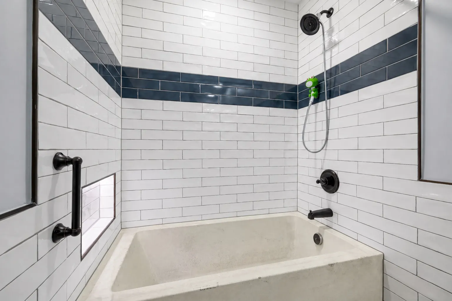 Subway-tiled bathtub alcove with a stained, worn off-white tub before refinishing